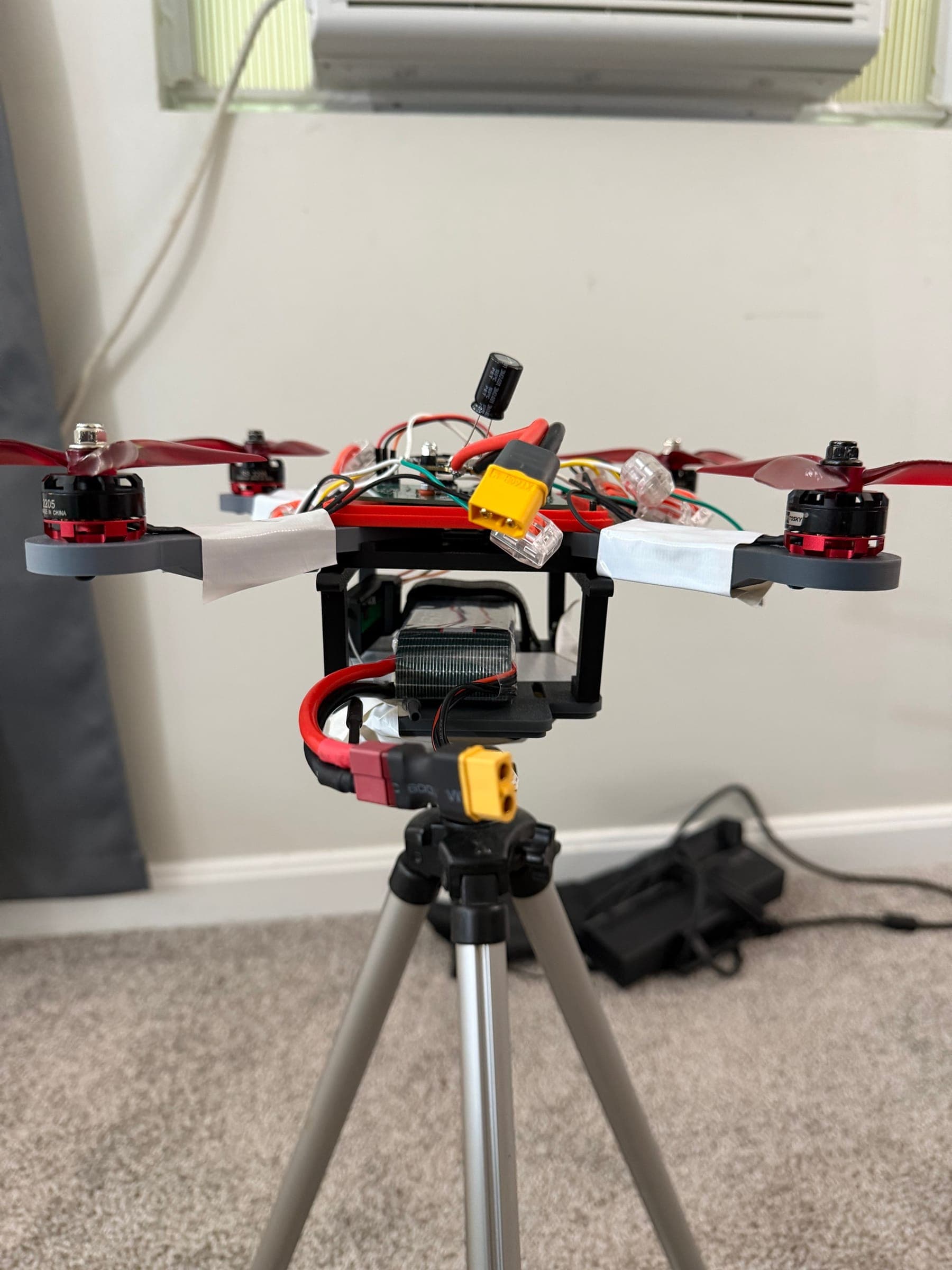 The finished quadcopter with the custom flight controller, props and LiPo fitted, sitting on a tripod